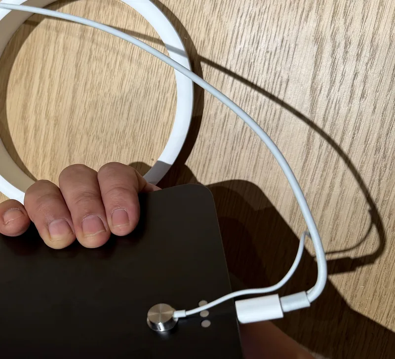 Style reference photo taken at an Apple Store: round contact sensor on the back of a device held for a hands-on demo (not a Tocvue product)